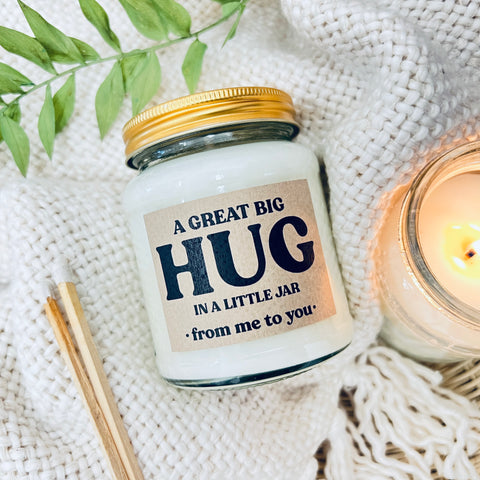 A Great Big Hug in a Little Jar - Scented Soy Wax Candle. A glass jar candle on a wool blanket with a plant in the background.